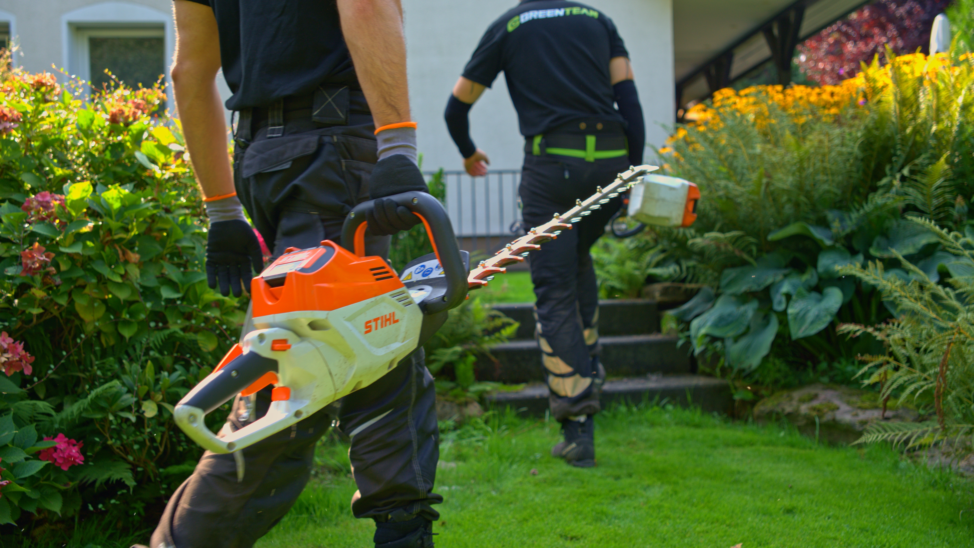 Grünflächenpflege Köln — GreenTeam Mitarbeiter mit Heckenscheren im Garten